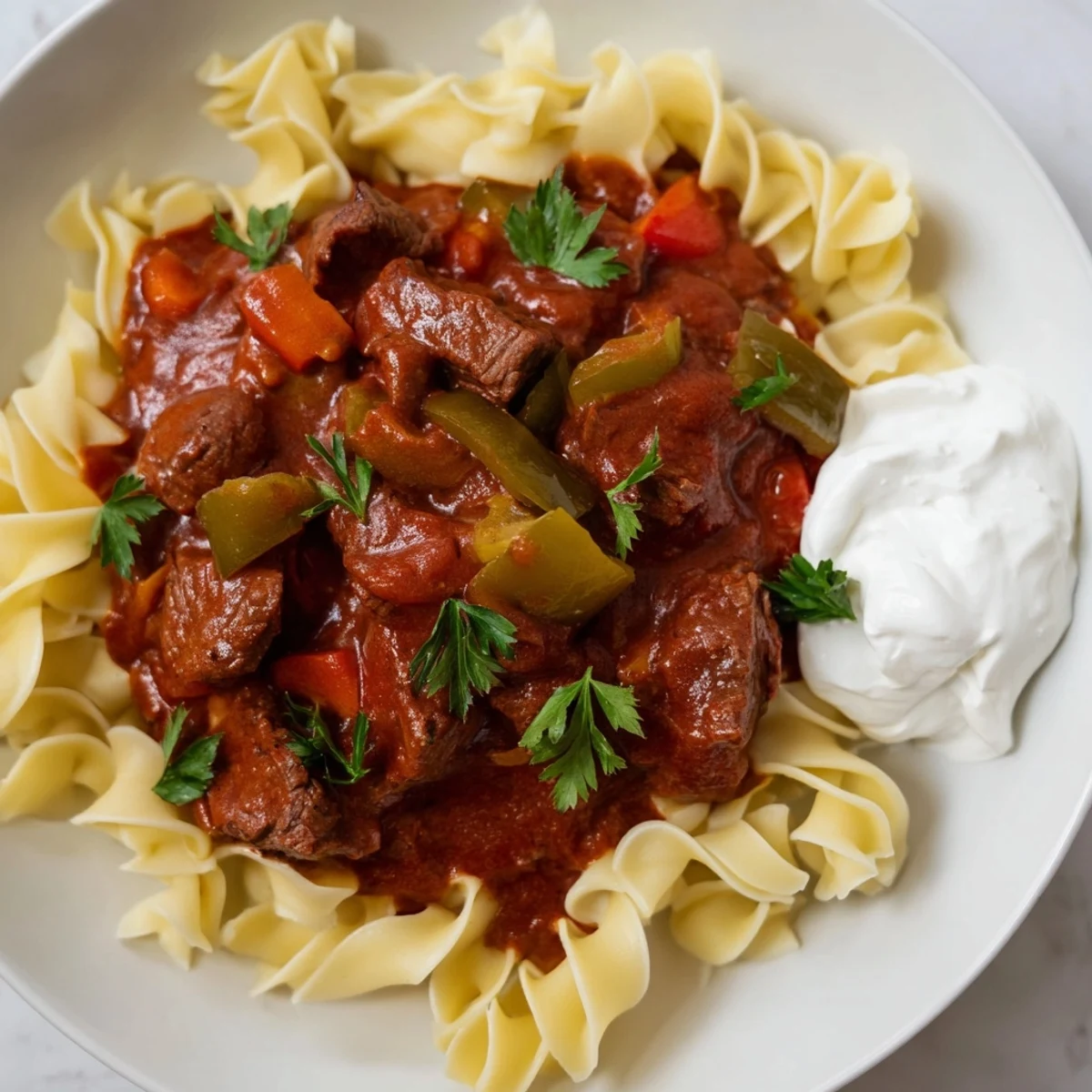 Hearty Hungarian Goulash stew, a rich, flavorful dish with steaming noodles, perfect for a cozy supper.
