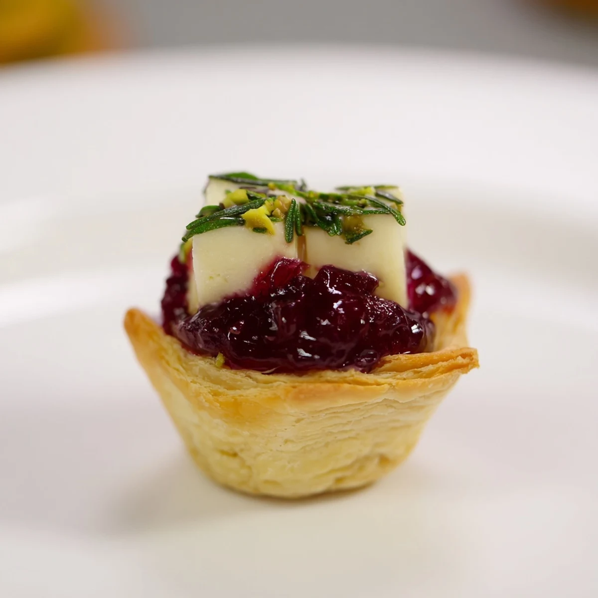 This gorgeous Mini Cranberry Brie Tart Wreath appetizer showcases baked tartlets garnished with fresh rosemary.