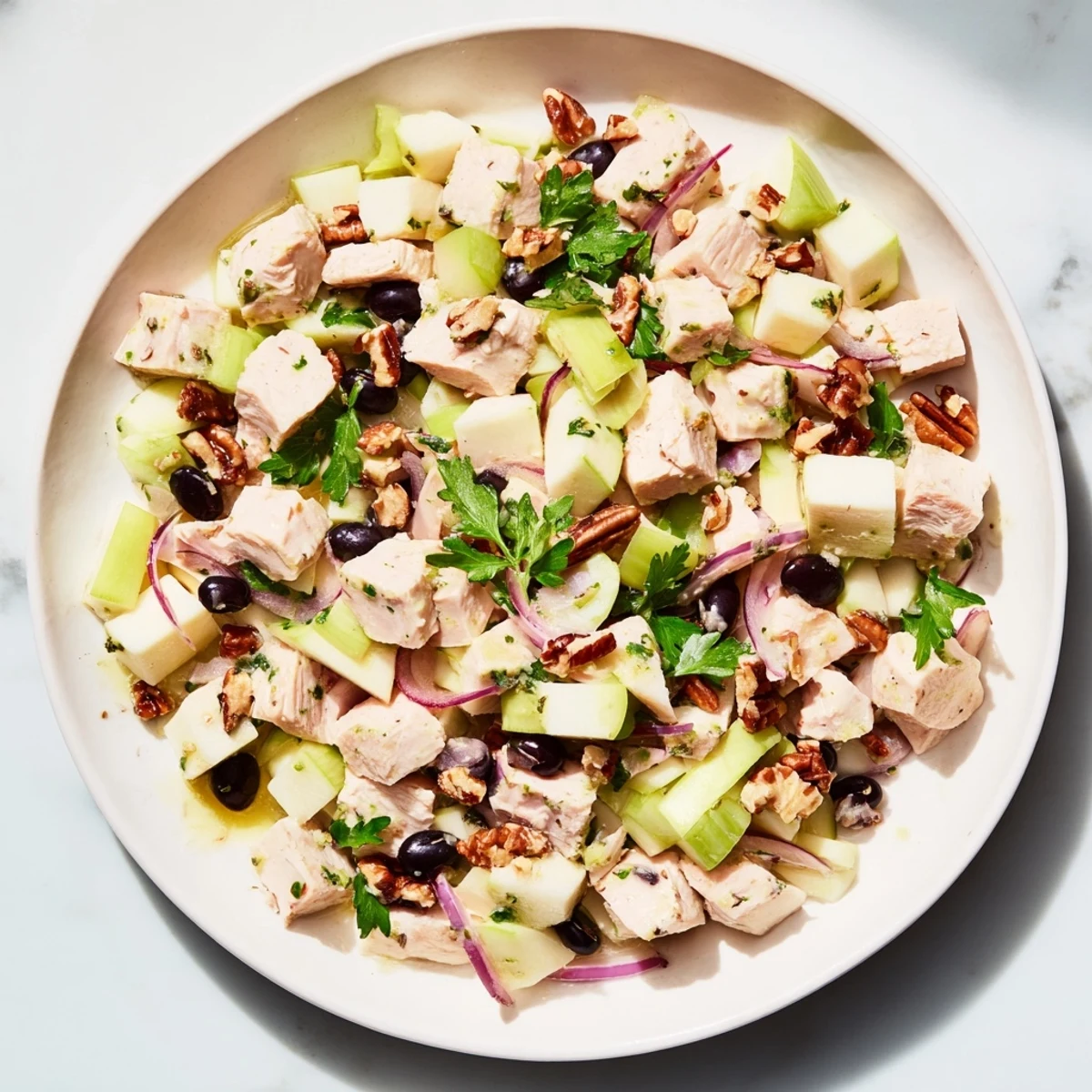 A colorful bowl of Chicken and Apple New Years Luck Salad, garnished with pecans, promises a delicious meal.