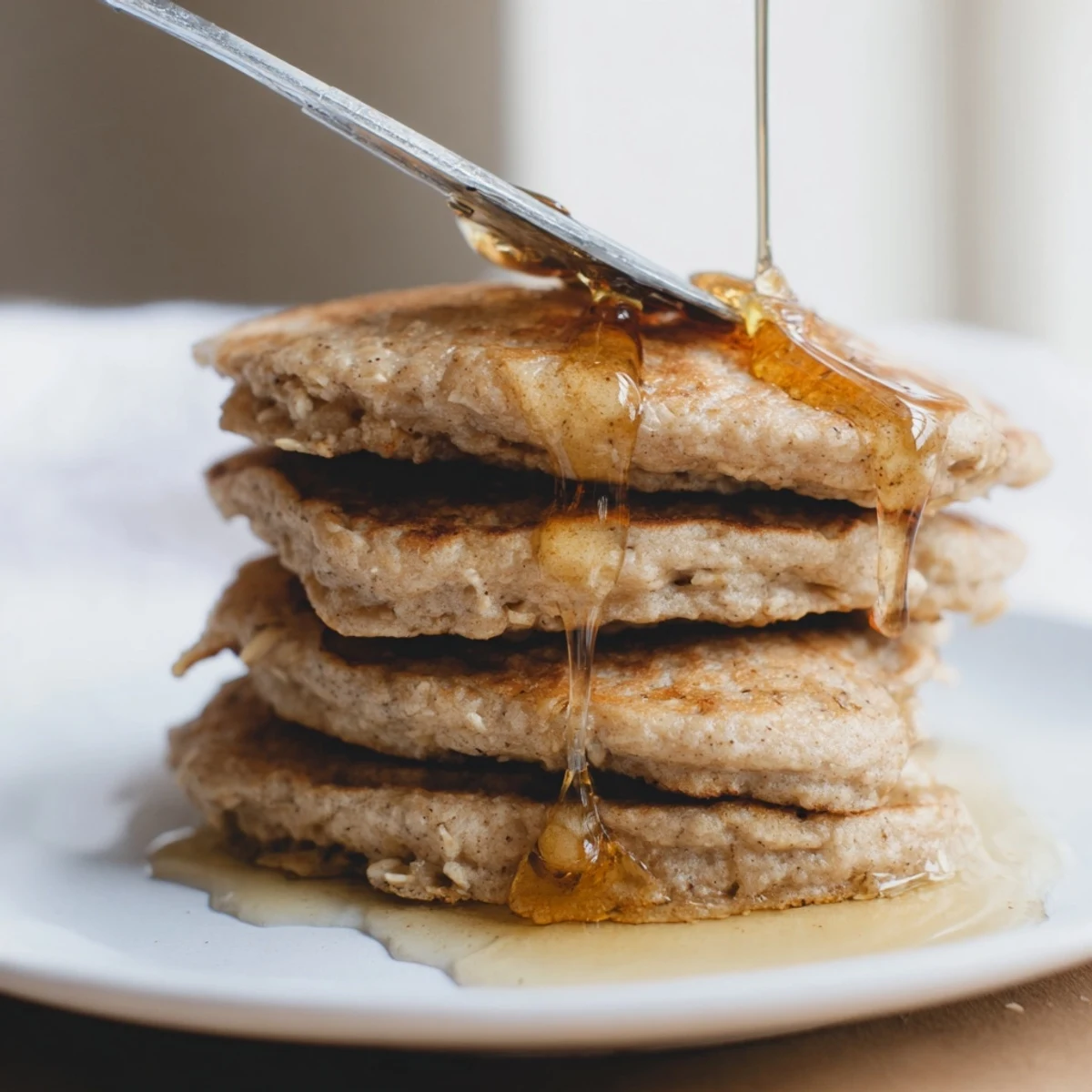 Golden-brown banana oat pancakes stacked high, ready to enjoy with fresh berries and syrups for breakfast.
