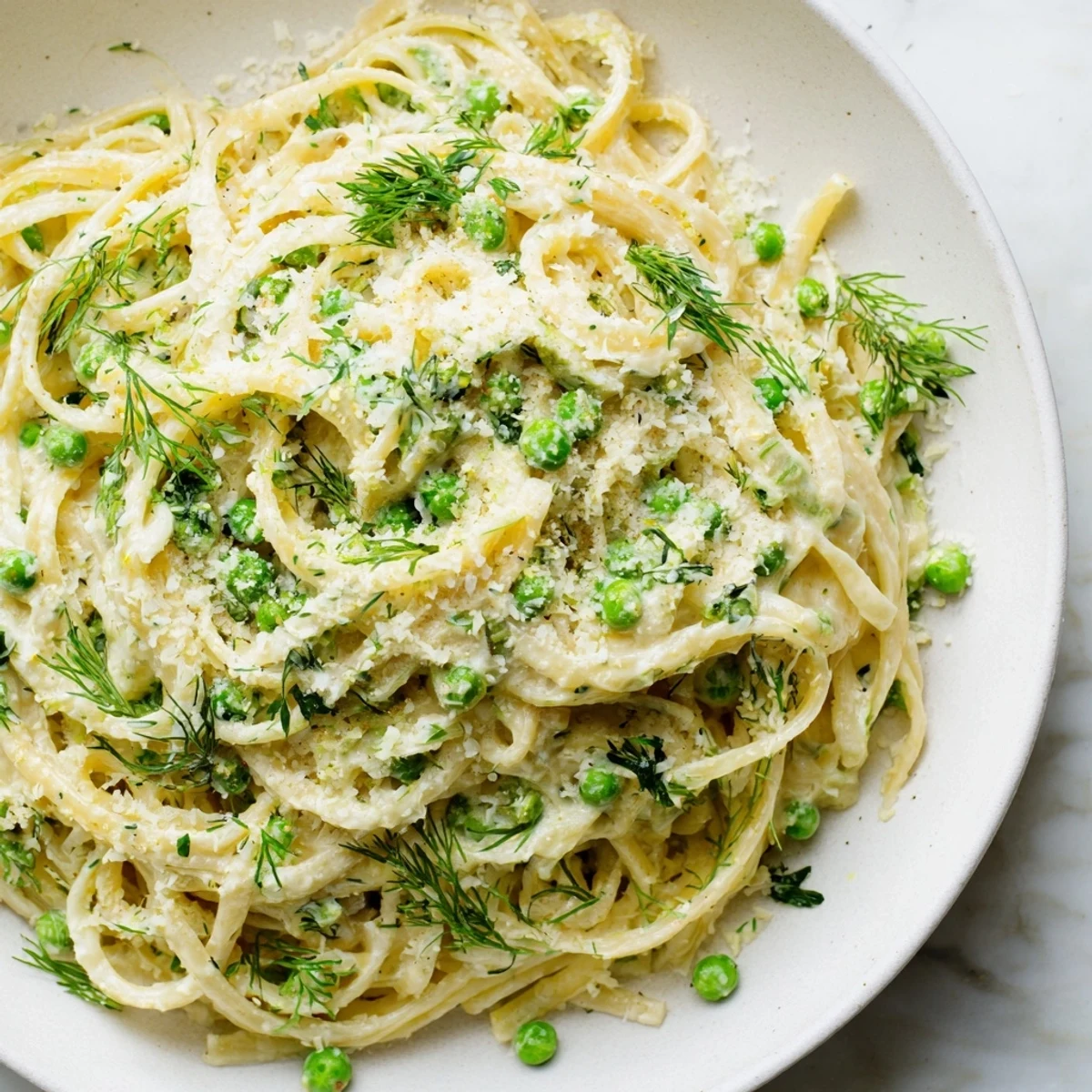 A close-up of a steaming bowl of Creamy Dill Pasta, garnished with fresh dill and lemon zest.