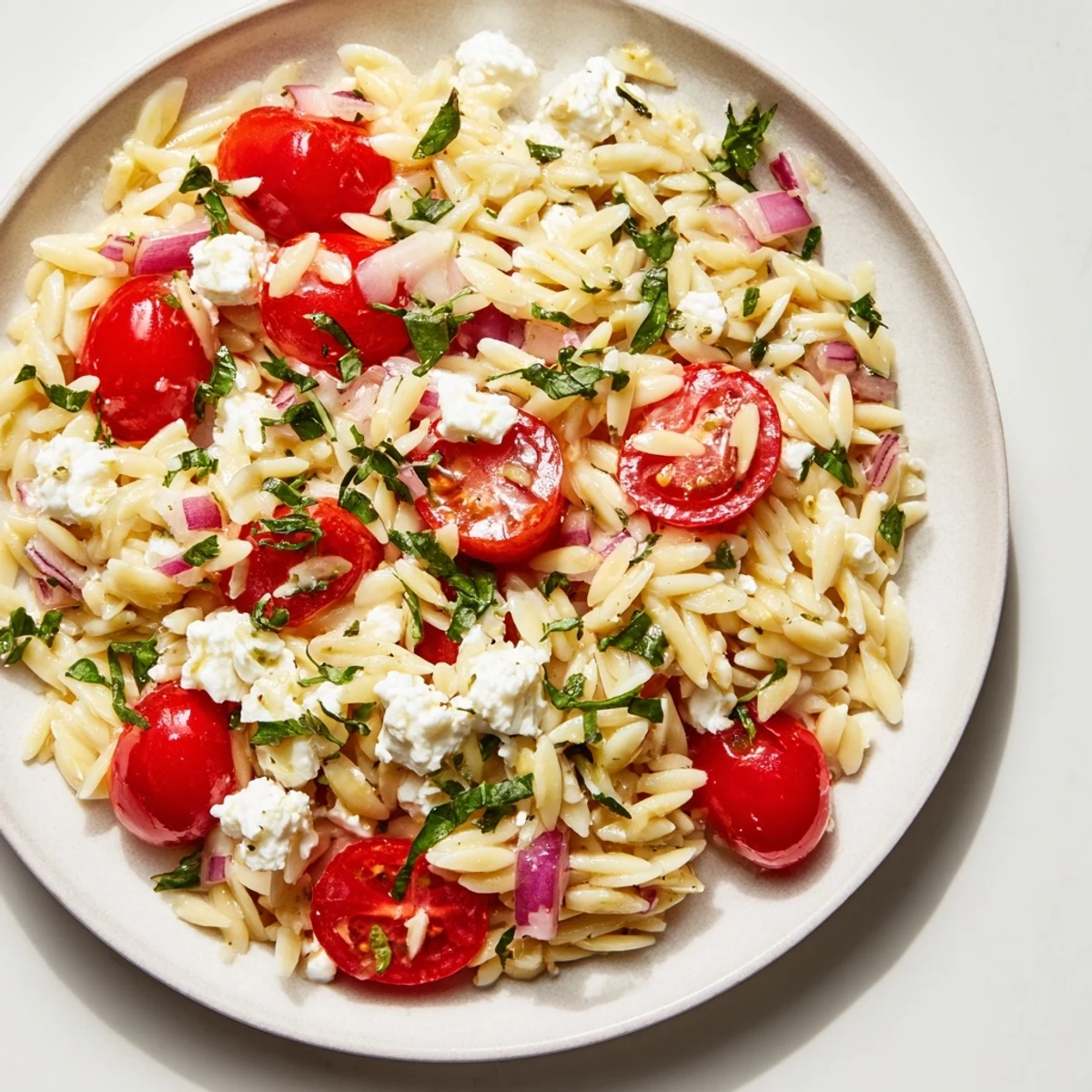 Vibrant Tomato Feta Orzo pasta salad with glistening olive oil and crumbled feta cheese.