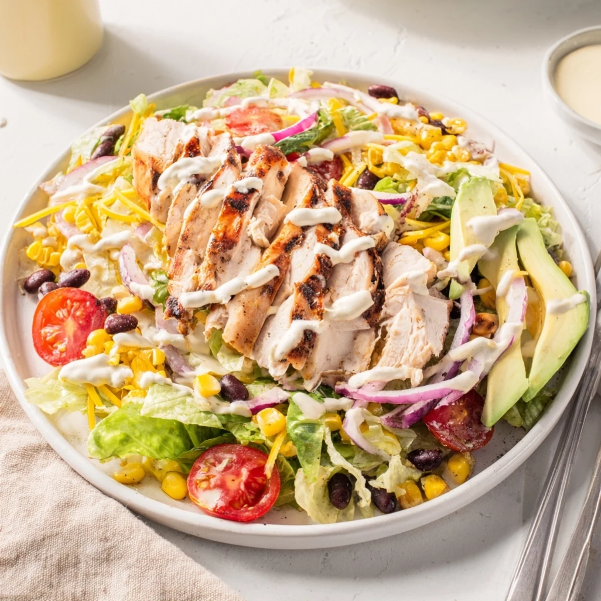 Sliced smoky BBQ chicken rests on crisp romaine with grilled corn, black beans, and creamy ranch drizzle in this vibrant salad.
