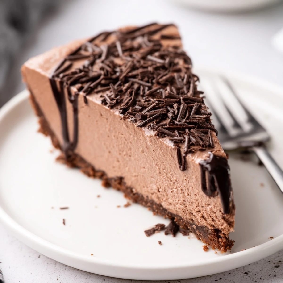 Overhead shot of a whole Lighter Chocolate Cottage Cheese Cheesecake in a springform pan, garnished with fresh raspberries and a dusting of cocoa powder.