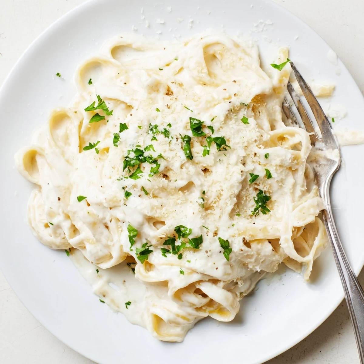 Steaming bowl of Easy Creamy Cauliflower Alfredo, featuring tender pasta in a light, dairy-free sauce with fresh parsley.
