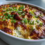 Freshly baked Buffalo Chicken Dip, creamy and spicy, scooped from a dish alongside crisp celery sticks and carrot sticks.