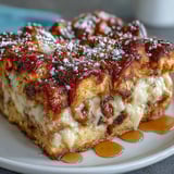 Monte Cristo Breakfast Casserole served warm with fresh berries and a drizzle of syrup.