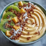 This refreshing smoothie bowl blends sweet mango, tangy lime, and a hint of chili heat, served with crunchy granola and tropical fruit toppings.