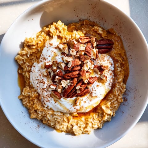 Steaming bowl of Pumpkin Spice Latte Oats, topped with whipped cream and chopped pecans.