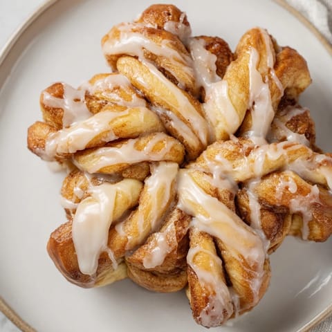 Warm, shareable pull-apart cinnamon roll snowflake with glistening icing, ready to be enjoyed.