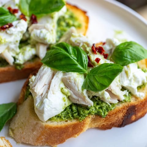 Sizzling Pesto Chicken Burrata Toast ready to serve, garnished with red pepper flakes and extra basil.