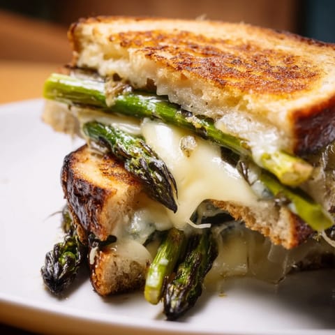 Golden Asparagus & Brie Grilled Cheese with melted cheese on a rustic wooden cutting board.  
