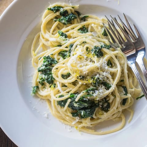 A close-up of Creamy Lemon Spinach Spaghetti piled on a white plate, showcasing vibrant green spinach and zesty lemon zest.