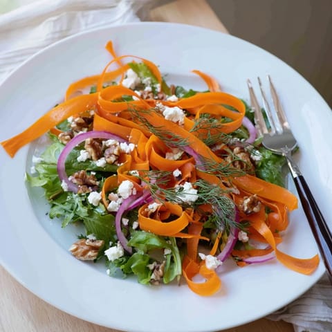 Golden, caramelized carrot ribbons atop mixed greens with feta, nuts, and fresh herbs.