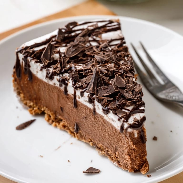 A close-up view shows the smooth, creamy texture of the Lighter Chocolate Cottage Cheese Cheesecake topped with a dollop of Greek yogurt and dark chocolate shavings.