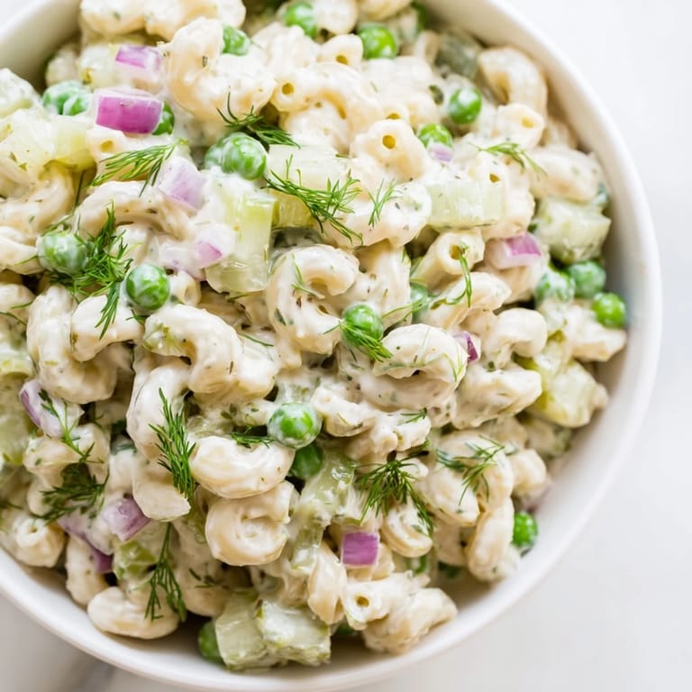Close-up view of creamy dill pickle pasta salad, highlighting the crunchy celery, red onion, and fresh dill garnish.